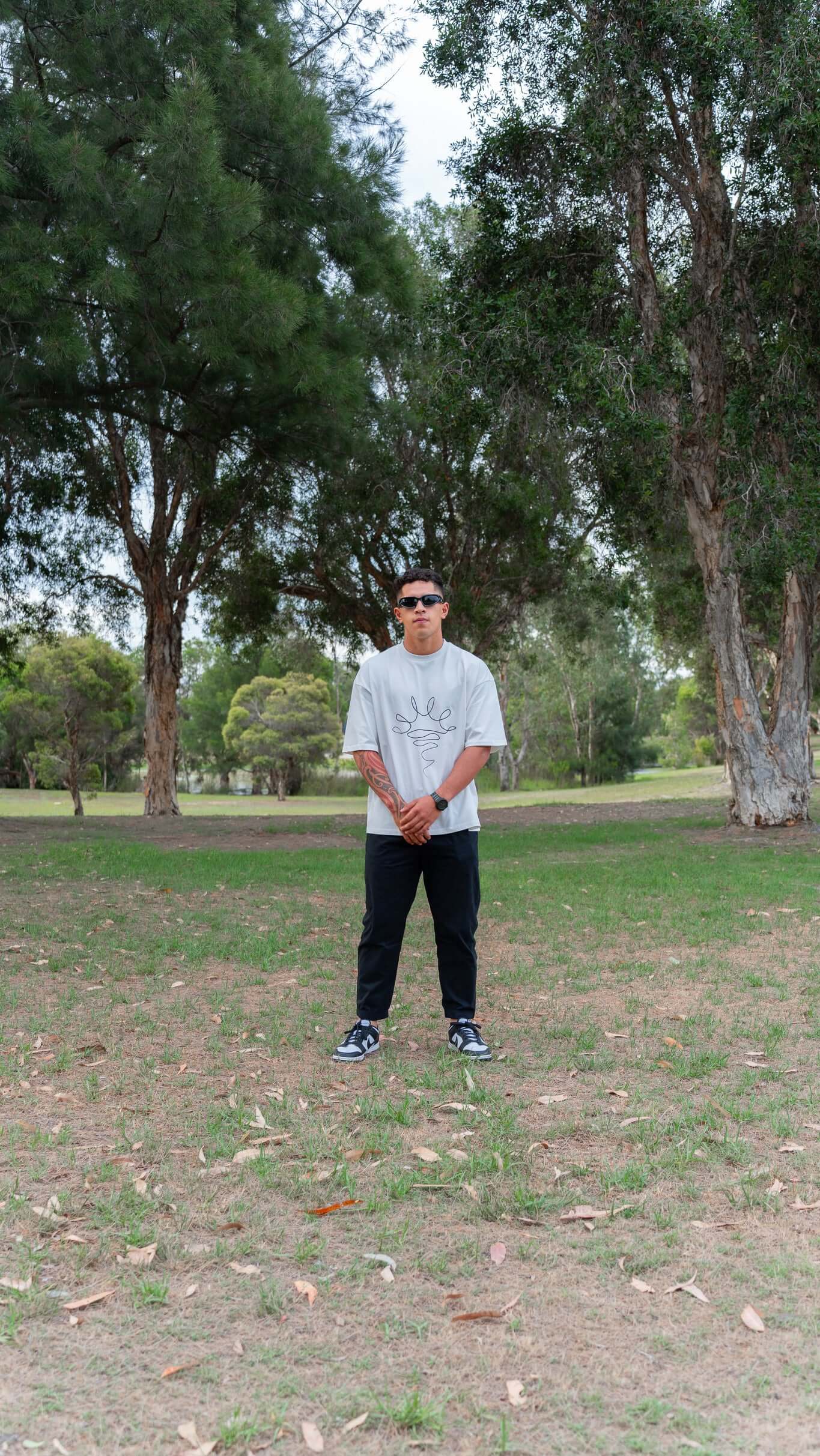 Male wearing white Tshirt, posing, standing in a park