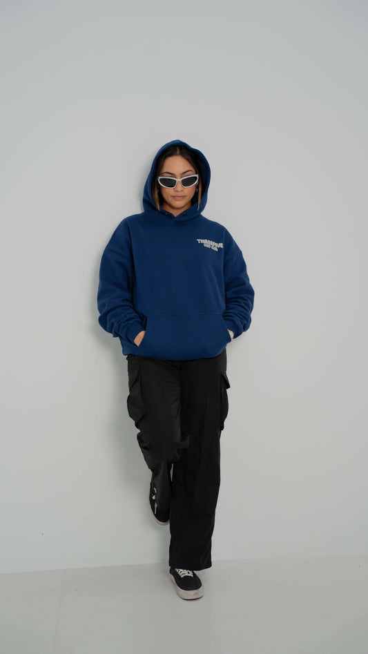 Female standing confidently wearing deep sea blue v2 hoodie