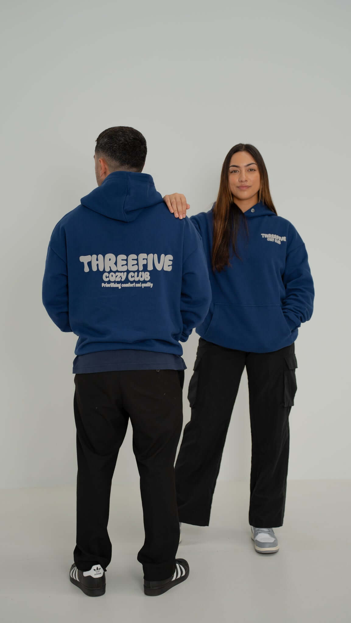 Female and Male standing confidently wearing deep sea blue v2 hoodie