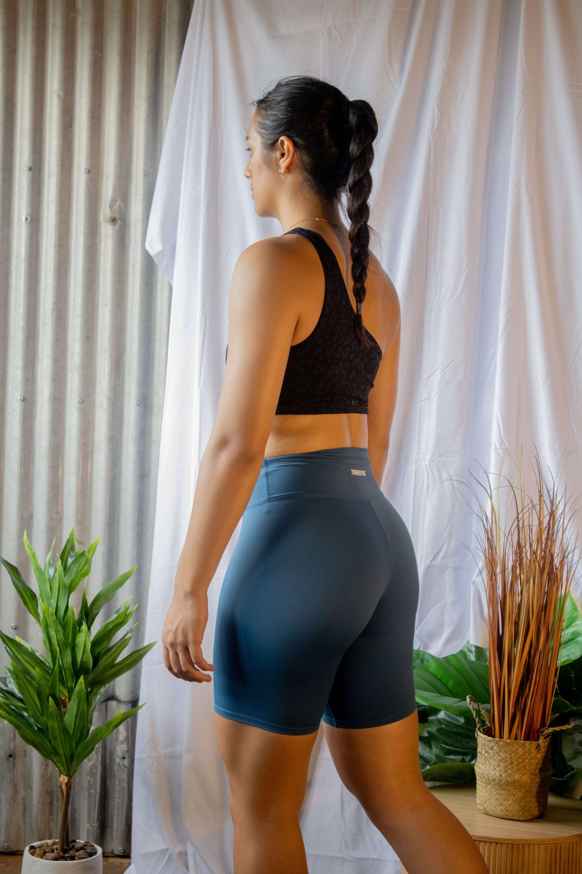 Female wearing blue bike shorts, pictured from the back, posing for photoshoot