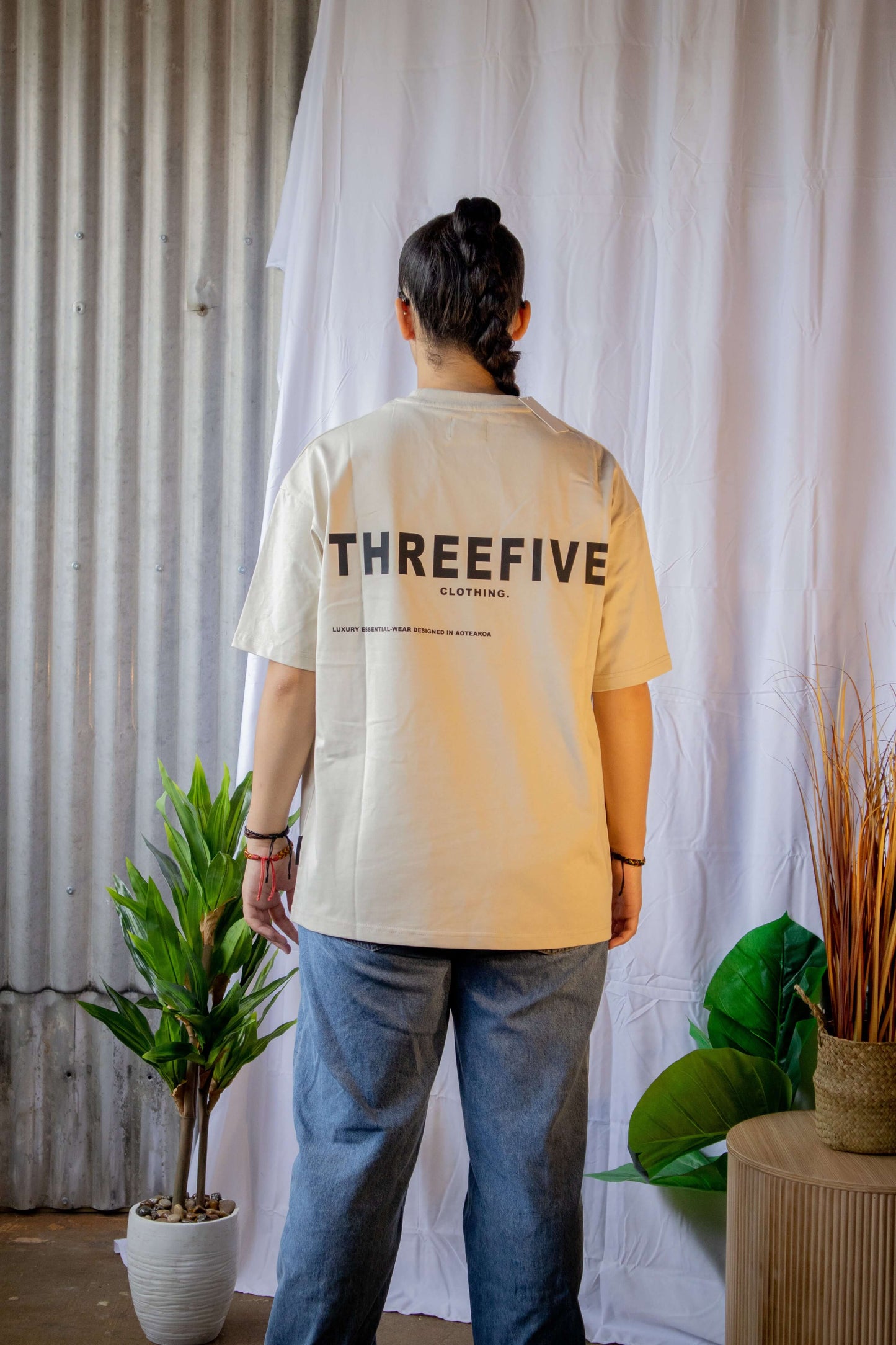Female standing, wearing bone coloured ThreeFive T-shirt, pictured from the back
